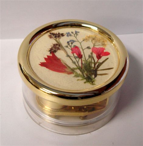 Clear round lucite music box with dried Swiss flowers.