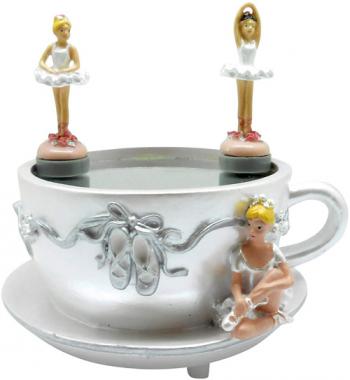 Two ballerinas dance on Cup while third sits and watches