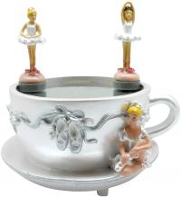 Two magnetic ballerinas dance on a teacup while a third sits by.